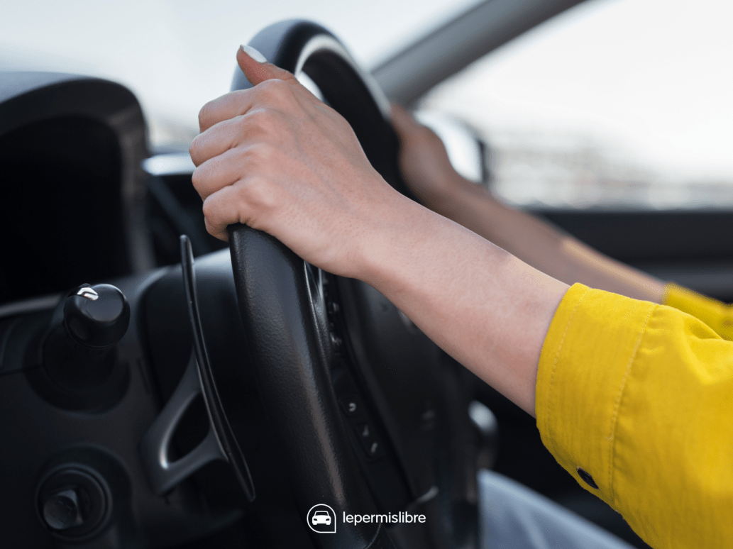 Mains positionnées sur un volant de voiture 